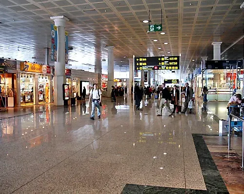 Taxi de Huelva al aeropuerto de Barcelona-El Prat: el interior de la terminal, con las pantallas de vuelos y las tiendas