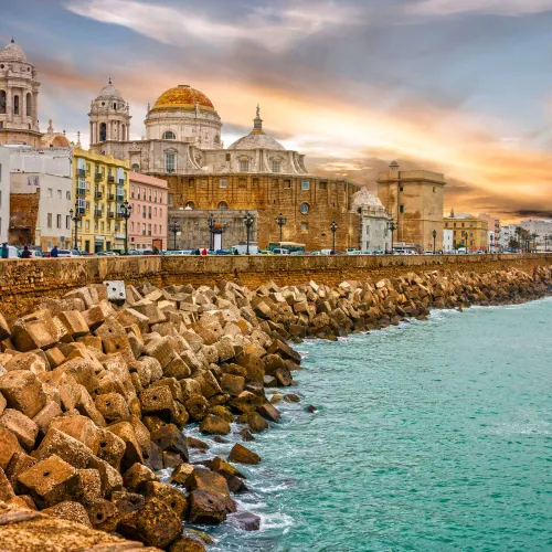 Taxi de Huelva a Cádiz: la Catedral vista desde el paseo marítimo, con el rompeolas de piedra
