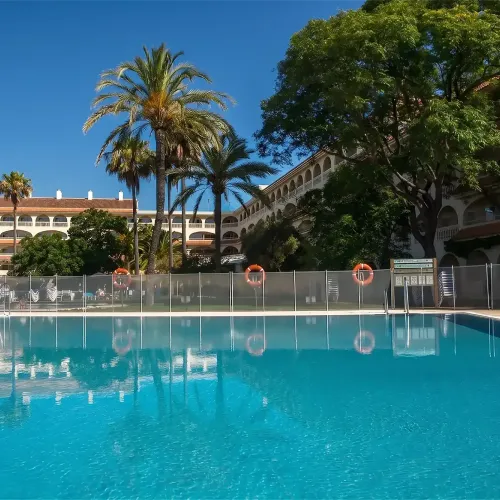 Taxi de Huelva al Gran Hotel del Coto, en Matalascañas: la piscina, entre palmeras y la fachada de arcos del hotel