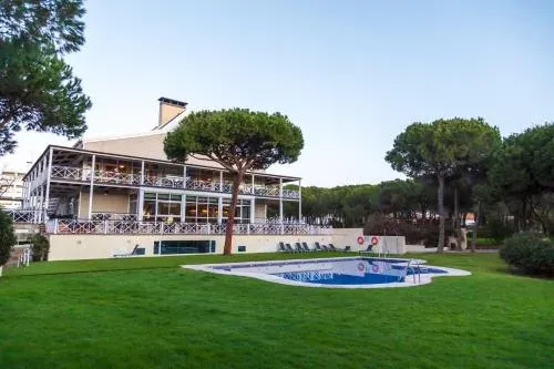 Taxi de Huelva al Hotel Nuevo Portil Golf, en Nuevo Portil: la piscina y la terraza del hotel, entre pinos