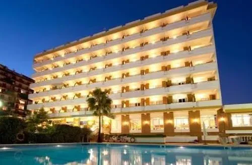 Taxi de Huelva al Hotel Pato Amarillo, en Punta Umbría: la fachada del hotel iluminada de noche, junto a la piscina