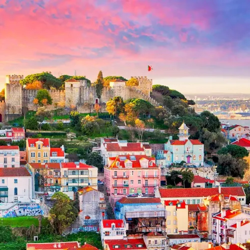 Taxi de Huelva a Lisboa: el Castillo de San Jorge sobre los tejados, al atardecer
